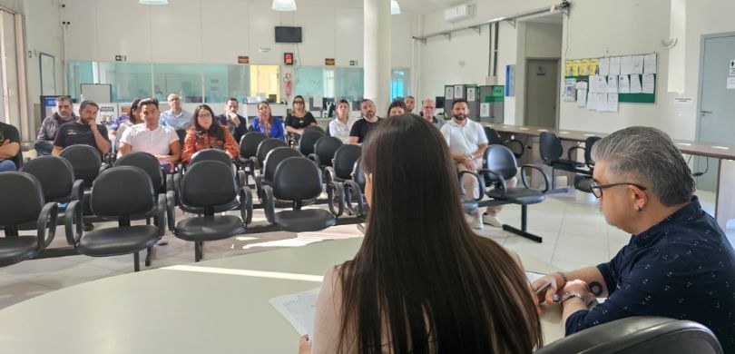 Fotografia de um homem e uma mulher sentados, de costas, em frente a uma mesa circular branca. E...