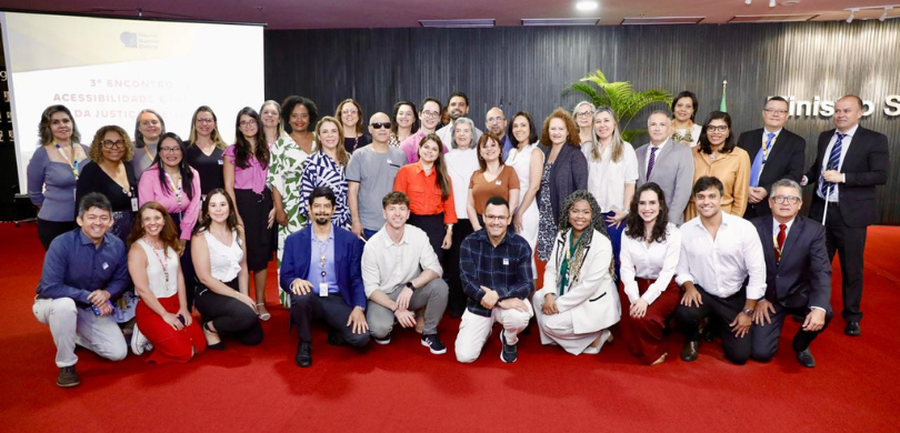 Fotografia de diversas pessoas, entre homens e mulheres, posando sorrindo organizadas em duas fi...