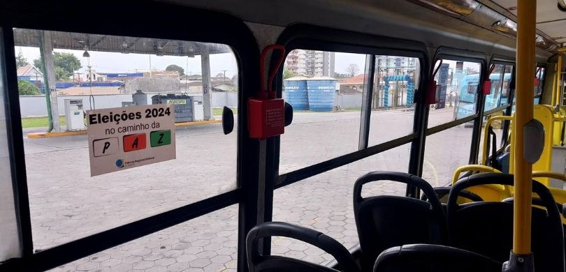 Fotografia do interior de um ônibus público, em que aparecem bancos nas cores cinza e amarela. O...