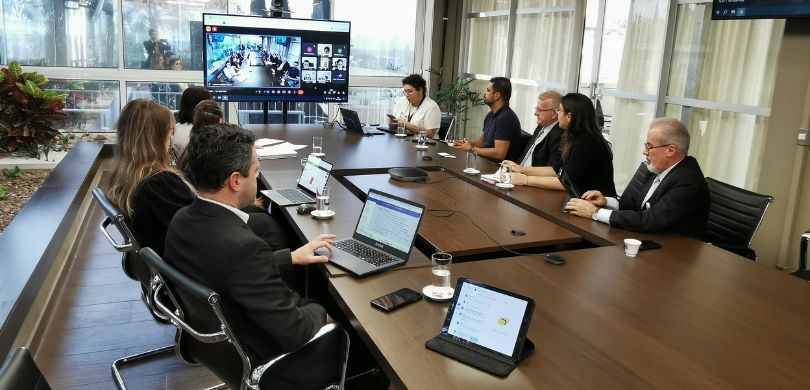 Foto em que se veem pessoas sentadas em torno de uma mesa de madeira, no terraço da Presidência ...