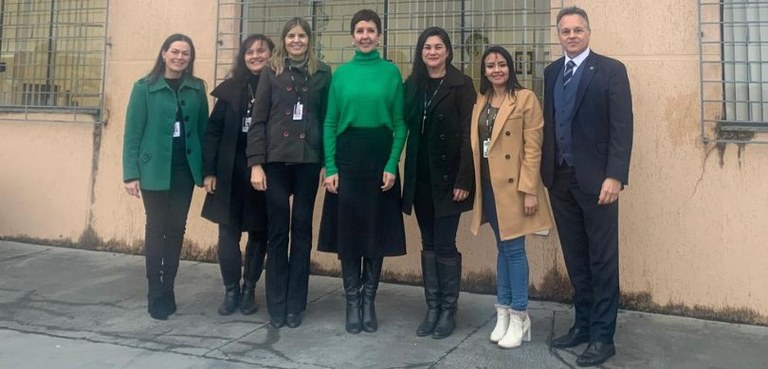 Fotografia de um homem de terno e seis mulheres, que vestem casacos de inverno e botas, posando ...