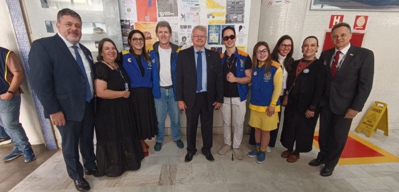 Fotografia de homens e mulheres lado a lado em um dos locais de votação. Atrás deles, é possível...