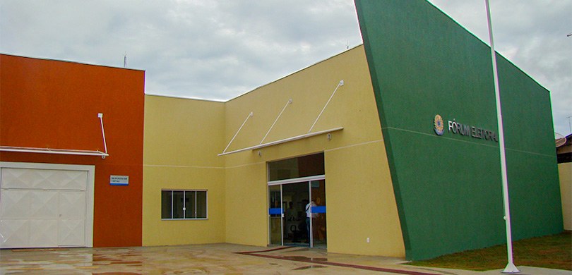 Fotografia do Fórum Eleitoral de Sertanópolis em um dia nublado. O edifício tem paredes na cor v...