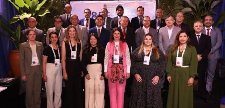 Fotografia de diversas pessoas posando sorrindo, organizadas em três fileiras. Na primeira filei...