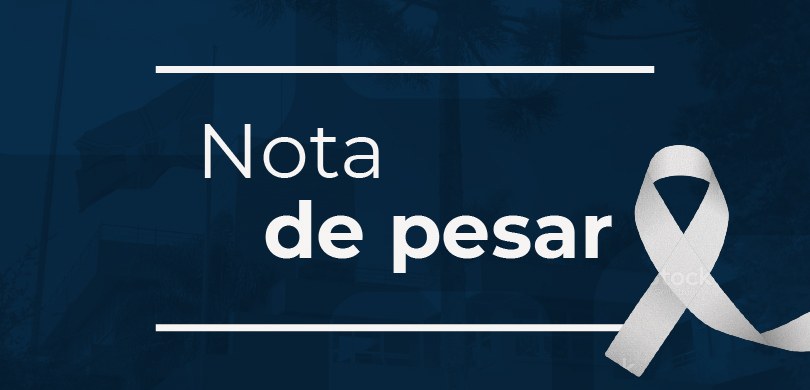 Banner em fundo azul, em que se lê: Nota de pesar. Do lado direito, há um laço branco. Ao fundo,...