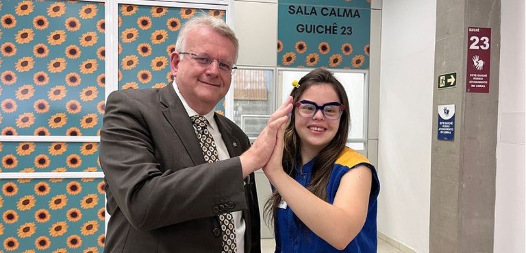 Pietra Silvestre e o desembargador Sigurd aparecem sorrindo para a foto. As palmas da mão direit...