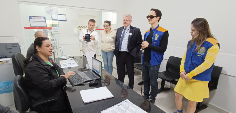 Fotografia de uma mulher e de um homem sentados em cadeiras em frente a uma mesa de mármore pret...