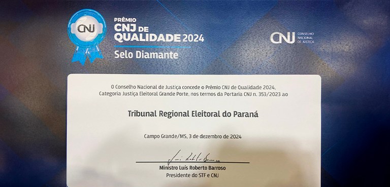 Foto em que aparece um diploma em azul e branco, em que se lê “Prêmio CNJ de Qualidade 2024 - Se...