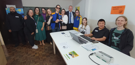 Fotografia de diversas pessoas, entre homens e mulheres, posando em um ambiente com paredes e pi...