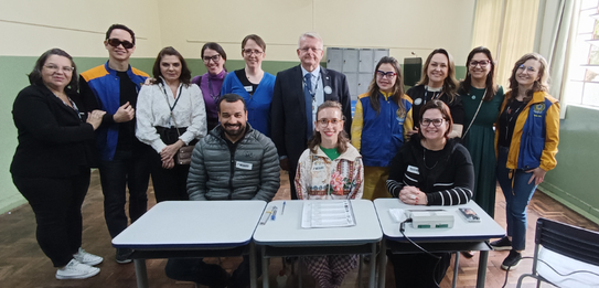 Fotografia de diversas pessoas, entre homens e mulheres, posando em um ambiente com paredes e pi...